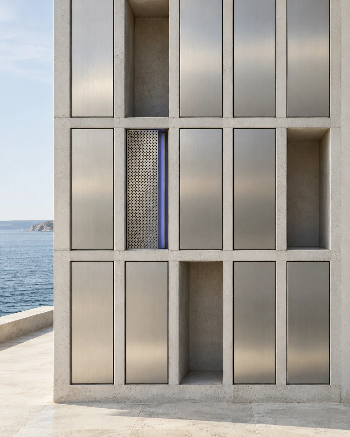 A concrete wall of tall compartments faced in brushed steel: most are closed, three stand open and empty, and one is closed behind a perforated steel screen with a strip of iolite glass.
