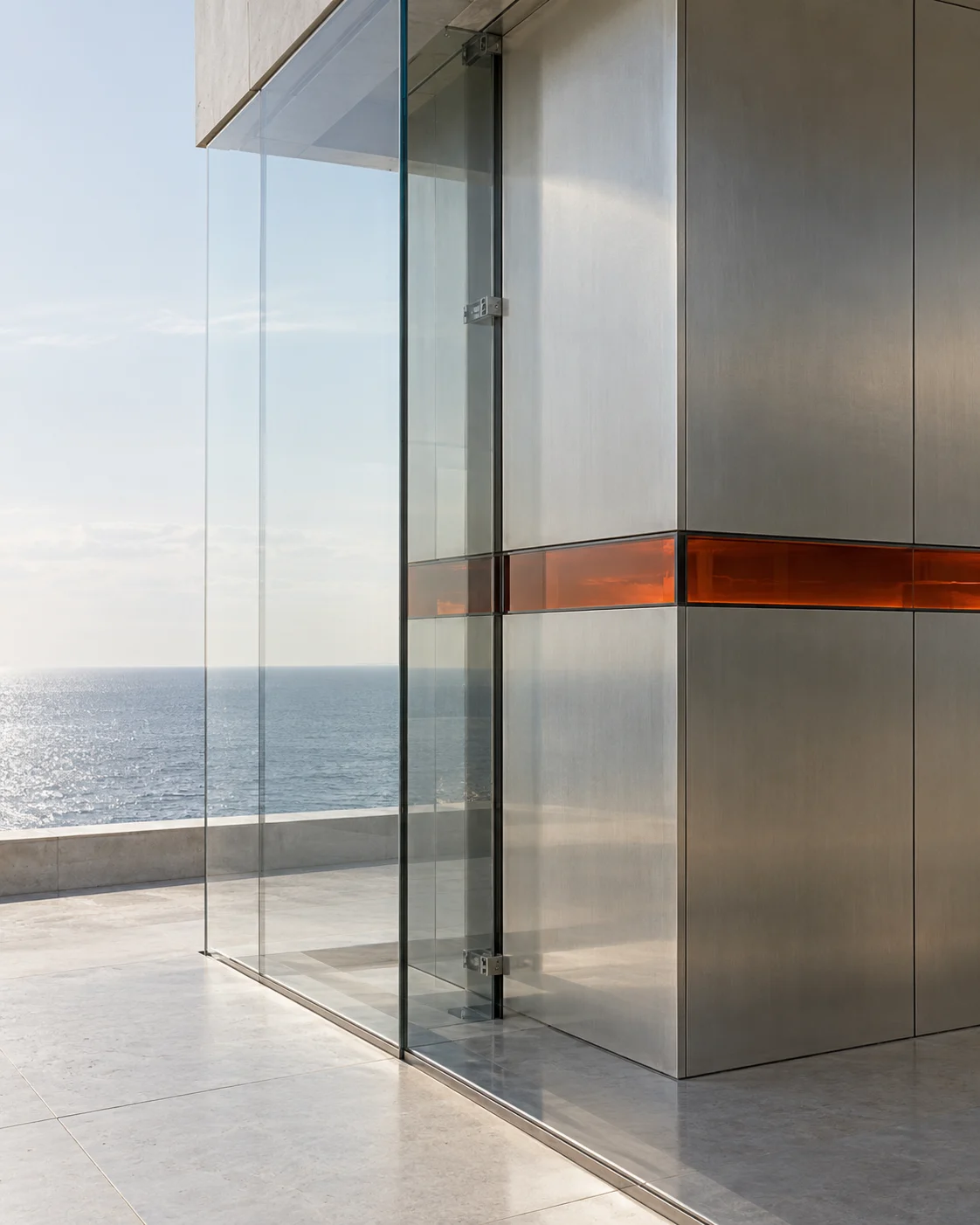 Close at one prism’s corner: the green-clear edge of thick glass, the brushed face of the steel core behind it and the air gap between them, with a band of carnelian glass crossing the frame once.