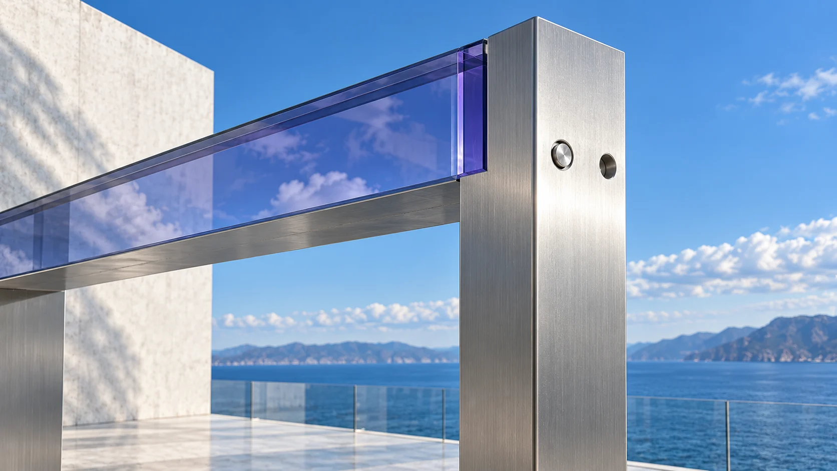 The joint where a lintel of iolite glass meets its brushed steel post, close: two round fixings on the post, the sea and the sky beyond.