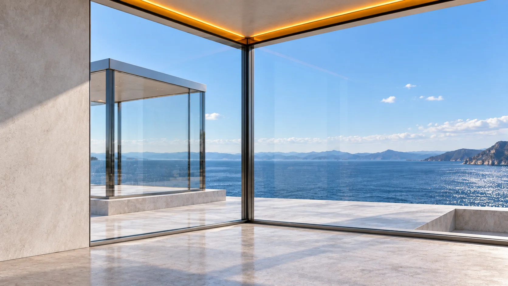 The view from inside one glass pavilion, out through its glass corner to the next pavilion and the sea: an open floor, a line of amber light along the ceiling edge, daylight.